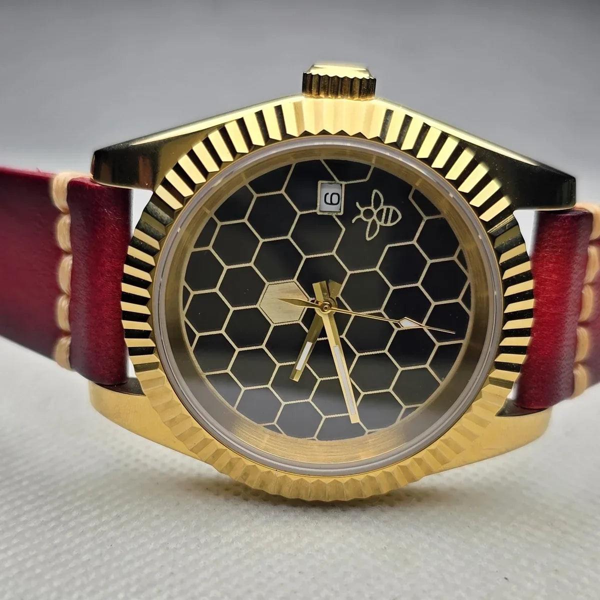 Gold-tone Rexx Honeycomb watch with a black and brass dial and burgundy leather strap