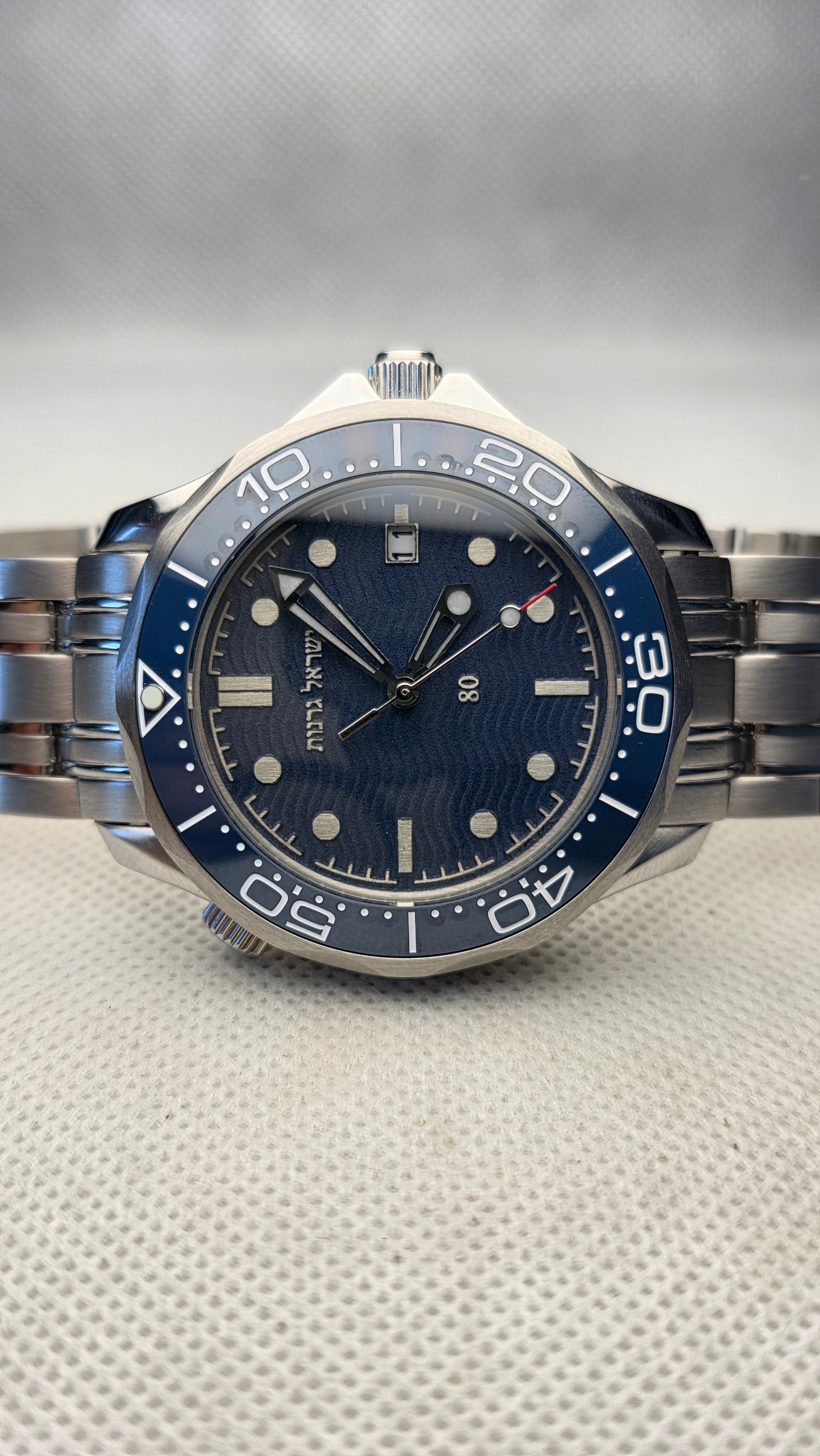 Blue custom dive watch with Hebrew lettering, engraved numerals and a steel bracelet