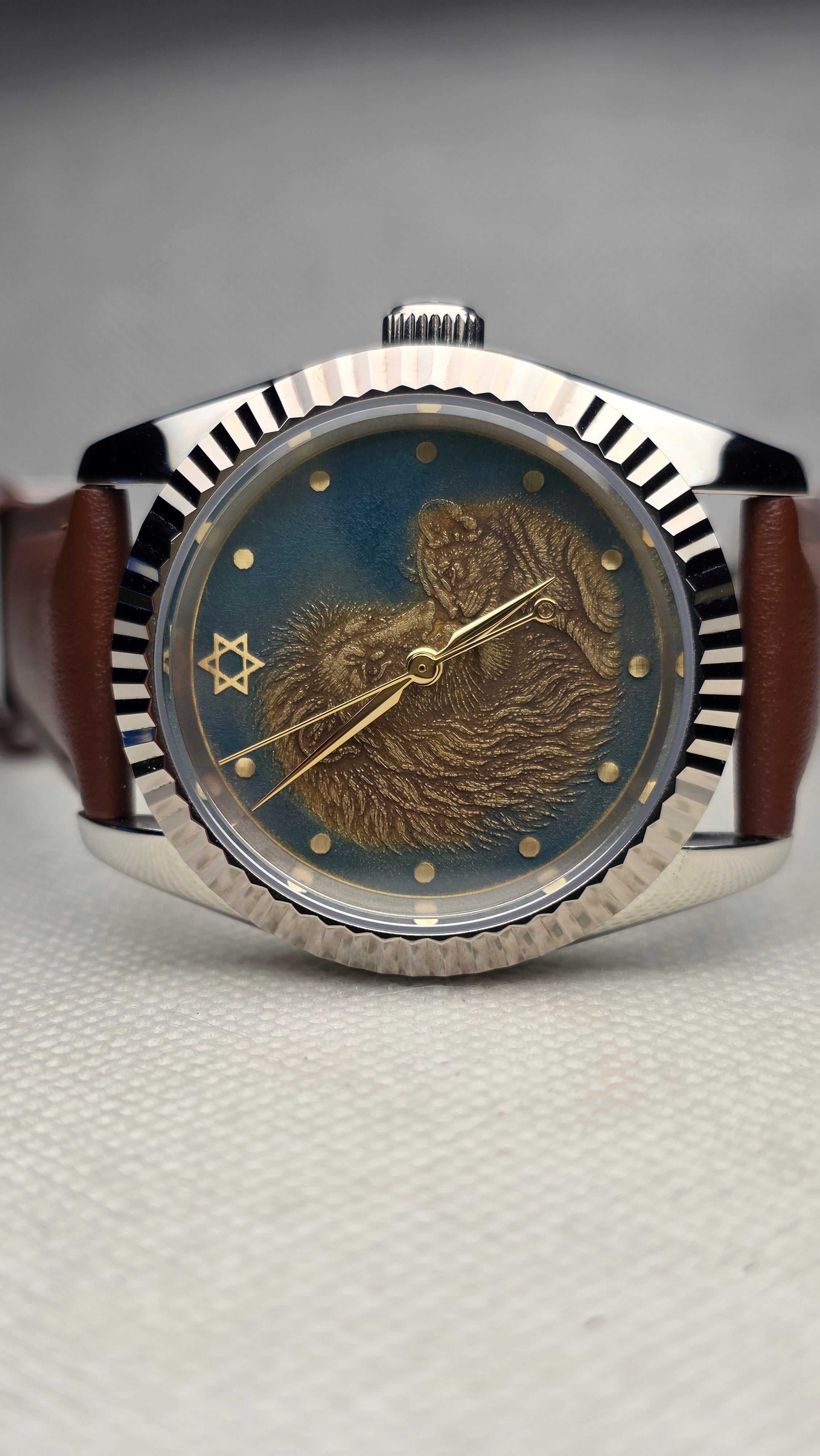 Green and brass story watch with two engraved foxes, a six-pointed star and a fluted bezel
