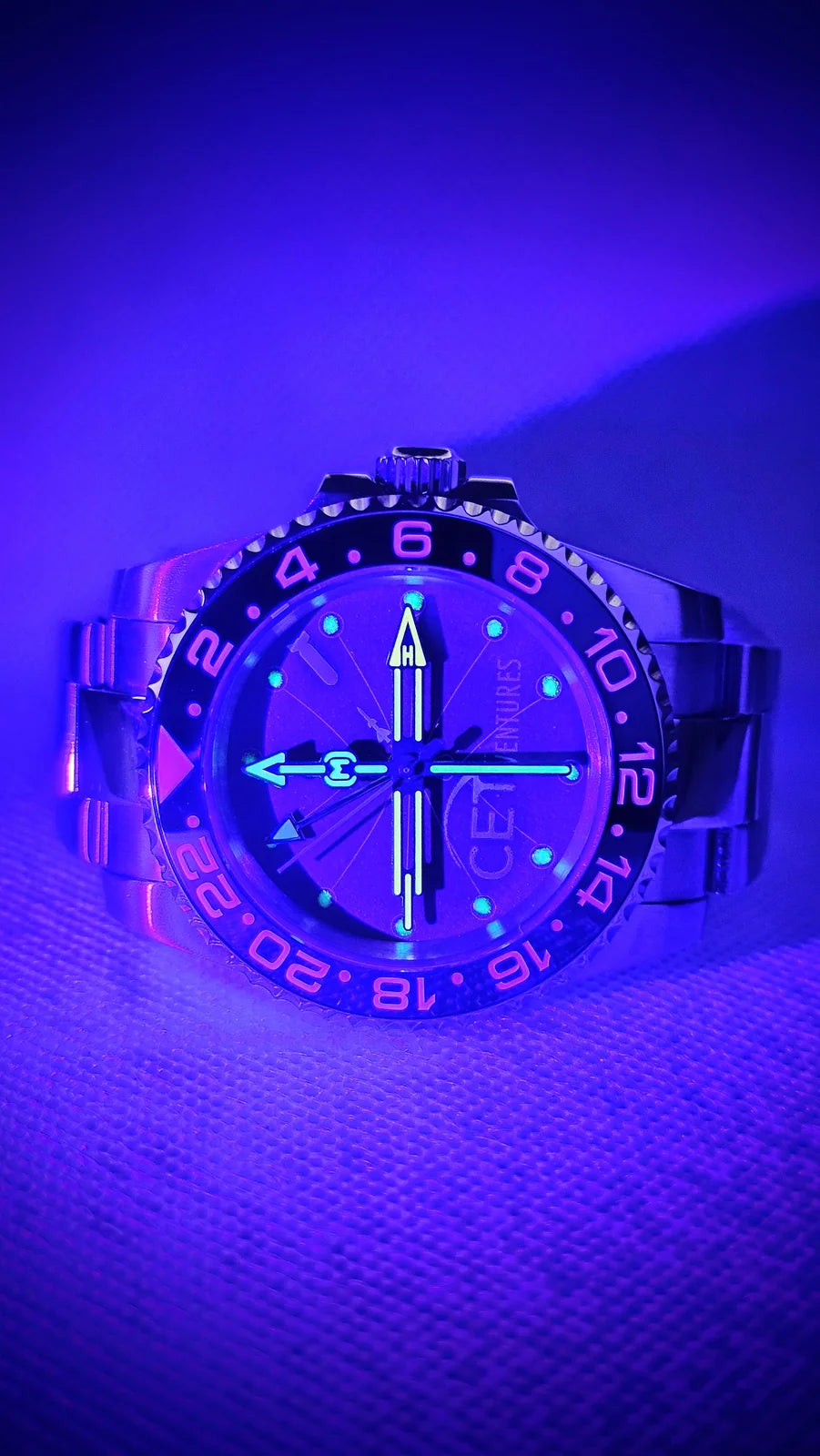 Custom steel sports watch glowing under ultraviolet light