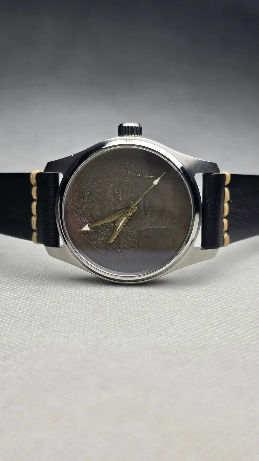 Dark engraved dress watch on a black leather strap