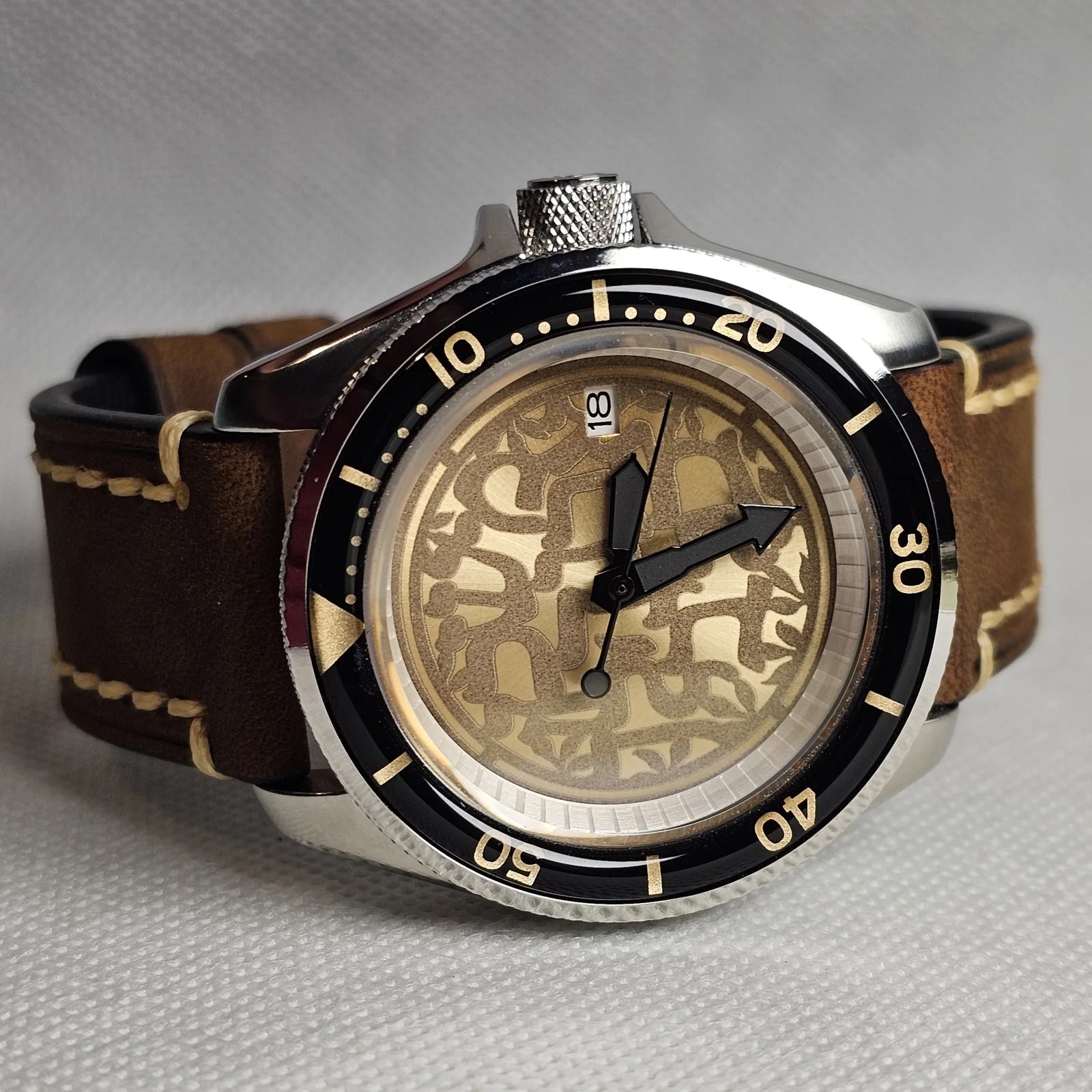 Gold and black custom sports watch with an engraved dial and brown leather strap