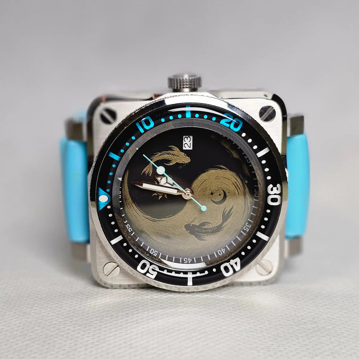 Square steel custom sports watch with a black and gold interlocking dragon dial and aqua strap accents