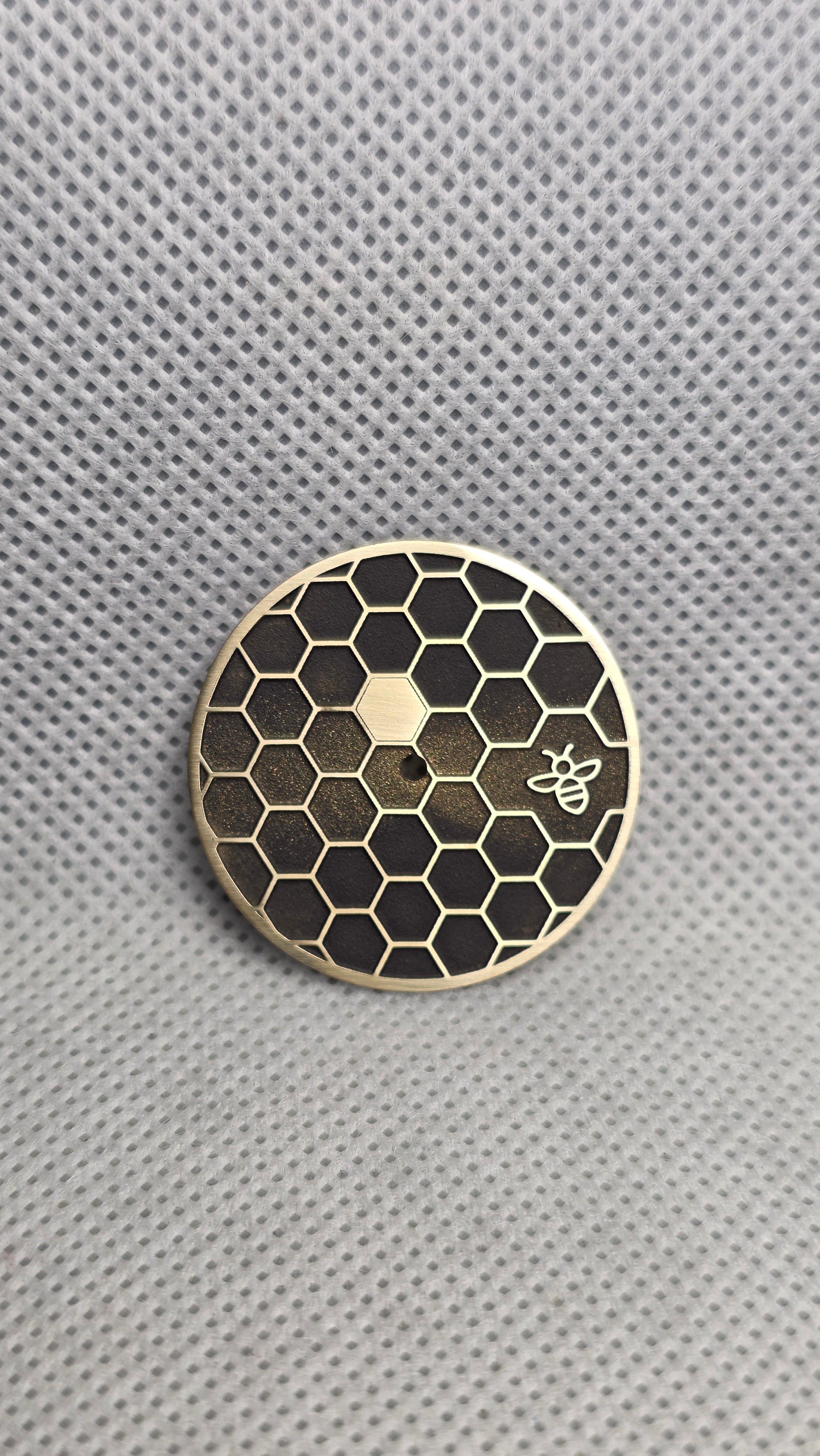 Brass custom watch dial with dark honeycomb cells, one solid hexagon and a small bee
