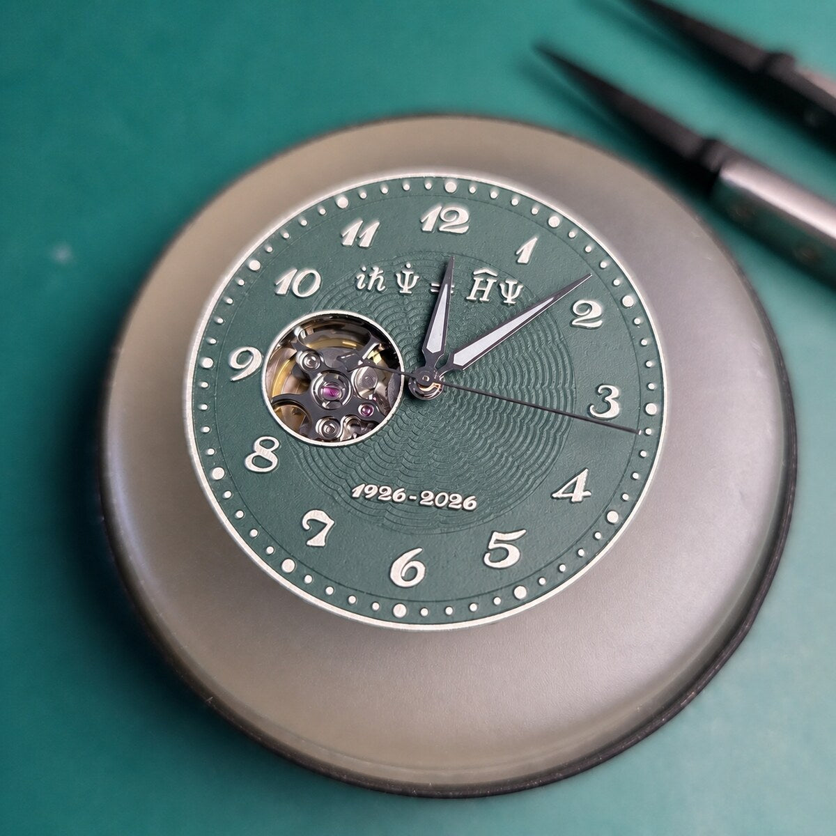 Green Schrodinger equation watch dial with open-heart aperture photographed at the workshop bench